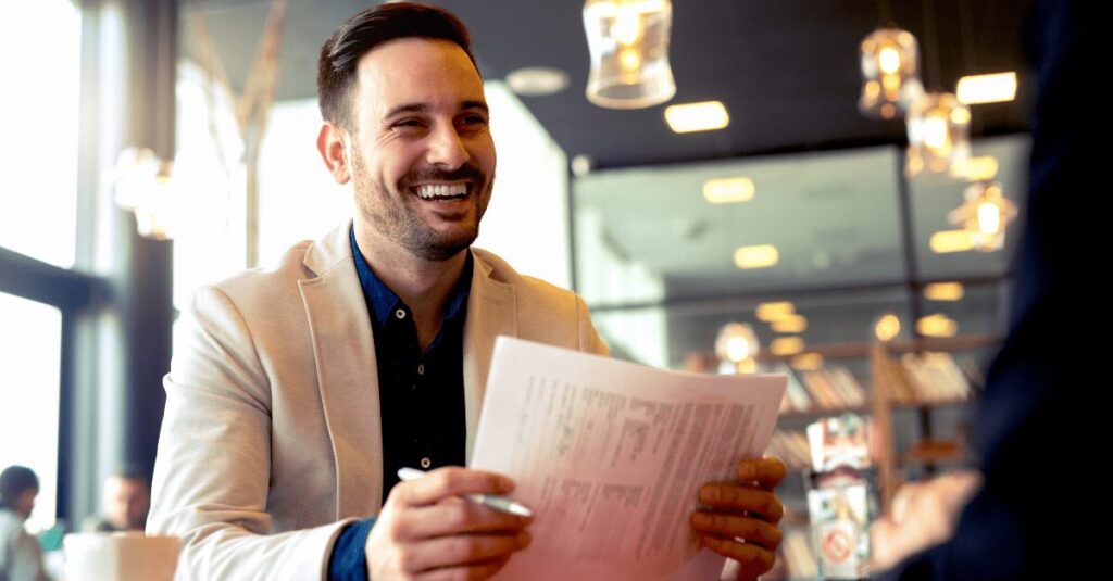 a businessman smiling and holding papers